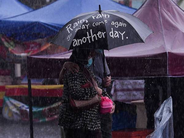 Orang ramai dilihat membeli juadah berbuka puasa meskipun hujan masih belum berhenti di Bazar Ramadan Kampung Baru pada hari pertama Ramadan hari ini.