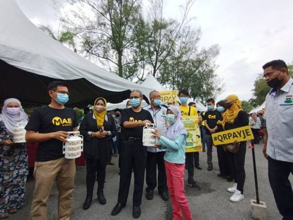 Rumaizi melakukan serahan mangkuk tingkat kepada pengunjung yang datang ke Bazar Ramadan Stadium di Ipoh pada Selasa.