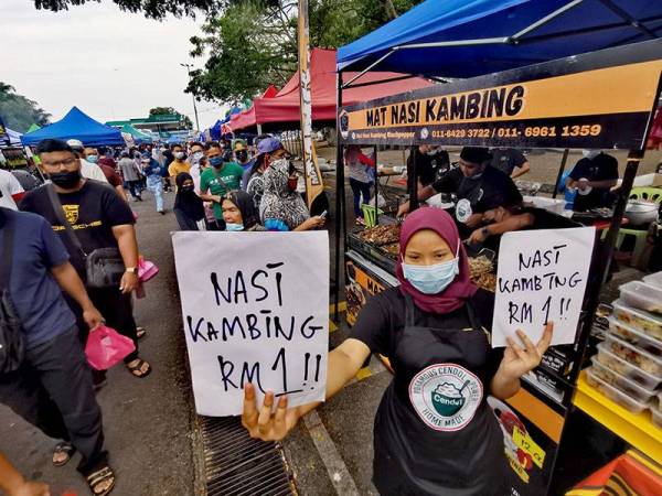 Pekerja gerai Mat Nasi Kambing PD memegang kertas tertulis nasi kambing RM1
