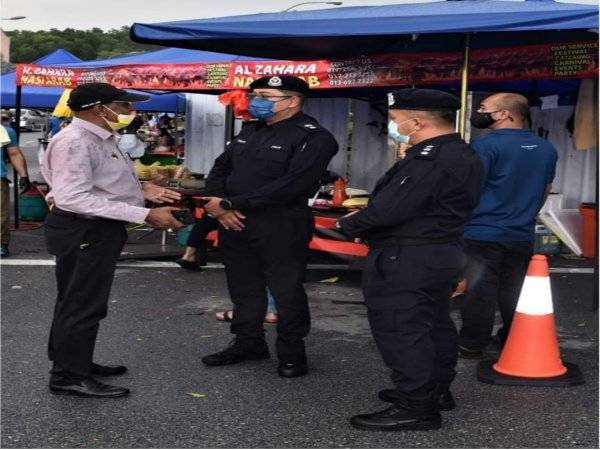 Mohd Fazley (tengah) berbincang dengan penganjur bazar Ramadan di Bandar Baru Nilai semasa lawatannya dalam Ops Pematuhan SOP pada Selasa.