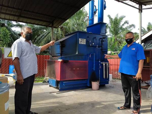 Ismail (kiri) dan Abd Rahman menunjukkan mesin Asher yang digunakan untuk memproses sisa buangan untuk dilupuskan.