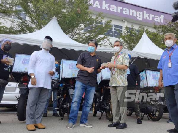 Ketua Pengarang Kumpulan Sinar Harian Rozaid Abdul Rahman (dua kanan) menerima bubur lambuk disampaikan wakil TV AlHijrah di Kompleks Karangkraf