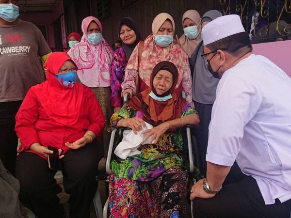 Sulaiman (kanan) menyantuni Nurisah (tengah, berkerusi roda) ketika melawat rumah mangsa yang musnah dalam kebakaran di Jalan Durian Daun, di sini, pada Khamis.