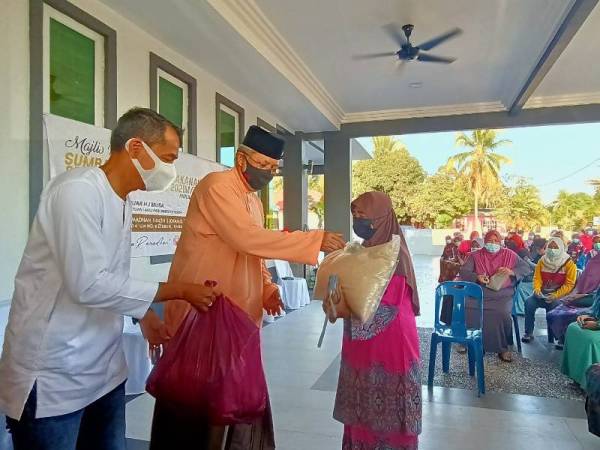 Annuar (dua dari kiri) menyampaikan sumbangan pada Majlis Penyampaian Bakul Makanan sempena Ramadan Parlimen Ketereh di Padang Halban, Kota Bharu pada Khamis.