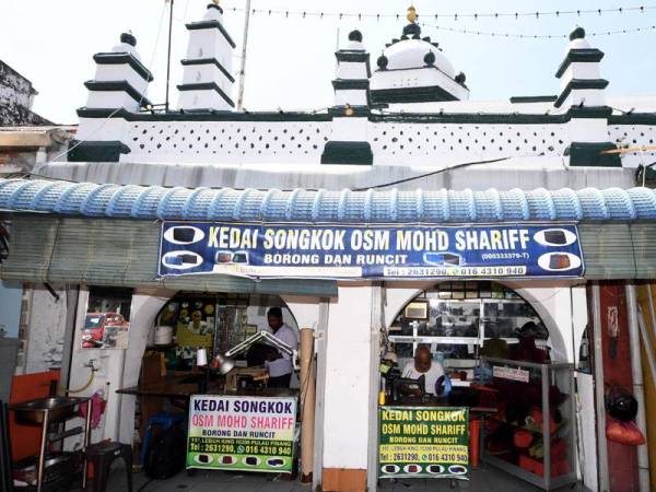 Haja Mohideen Mohd Shariff, 72, (kanan) menyiapkan tempahan songkok pelanggan di dalam sebuah kedai di bangunan warisan bersebelahan dengan Masjid Nagore di Lebuh King di sini. - Foto Bernama