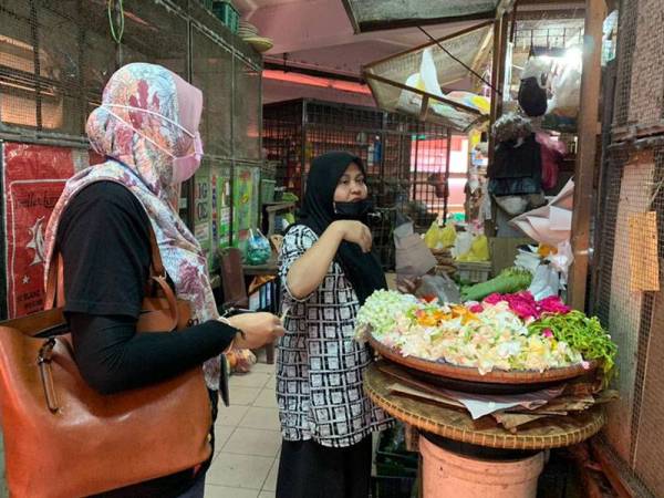 Zira (kiri) tidak melepaskan peluang membeli bunga di gerai Sabariah.