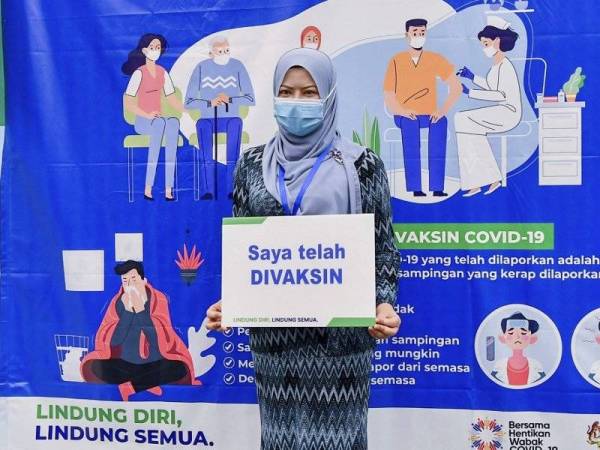 Rina memegang playkad 'Saya telah DIVAKSIN' selepas menerima suntikan vaksin Covid-19 di Pusat Pemberian Vaksin Wilayah Persekutuan Putrajaya pada Jumaat. - Foto Bernama
