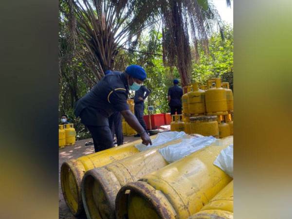 Pegawai penguat kuasa KPDNHEP Pulau Pinang sedang memeriksa tong gas LPG yang dirampas dalam serbuan di sebuah kebun kelapa sawit pada petang Jumaat.