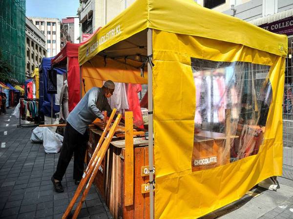 Peniaga melakukan persiapan sebelum memulakan perniagaan di Bazar Aidilfitri di Lorong Tuanku Abdul Rahman hari ini, yang telah beroperasi semula setelah ditangguhkan pelaksanaannya pada 2020 berikutan penularan COVID-19. - Foto Bernama