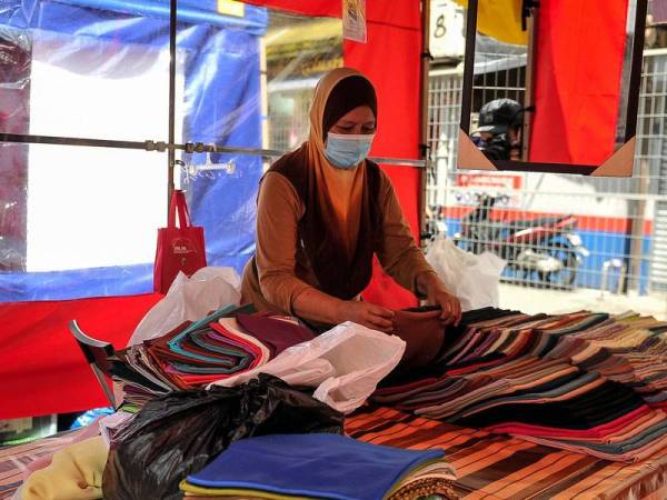 Peniaga melakukan persiapan sebelum memulakan perniagaan di Bazar Aidilfitri di Lorong Tuanku Abdul Rahman hari ini, yang telah beroperasi semula setelah ditangguhkan pelaksanaannya pada 2020 berikutan penularan COVID-19. - Foto Bernama
