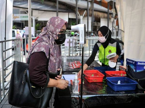 Orang ramai mematuhi Prosedur Operasi Standard (SOP) dengan memakai pelitup muka dan mengimbas suhu badan sebelum masuk ke Bazar Aidilfitri di Lorong Tuanku Abdul Rahman hari ini, yang telah beroperasi semula setelah ditangguhkan pelaksanaannya pada 2020 berikutan penularan COVID-19. - Foto Bernama
