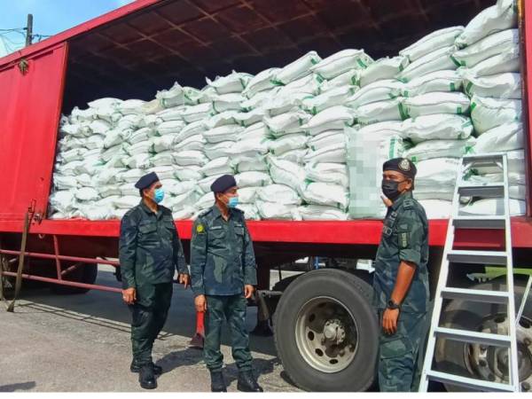 Sanudin (dua dari kiri) bersama Nor Azizan (kanan) menunjukkan 37,400kg beras bernilai RM138,800 yang disembunyikan dalam treler di sebuah stor dekat Kampung Bendang, Tanah Merah.