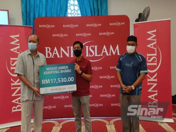 Mohd Muazzam (tengah) menyerahkan replika cek kepada Mohd Khay sebagai simbolik penyerahan wang zakat meliputi dana kepada pihak masjid dan agihan bubur lambuk di Masjid Jamek Kampung Baru, Kuala Lumpur pada Sabtu.