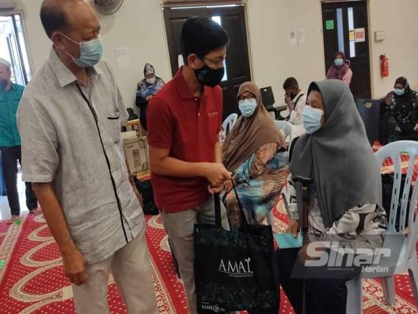 Mohd Khay (kiri) dan Mohd Muazzam memberikan wang tunai dan bakul makanan kepada asnaf di Masjid Jamek Kampung Baru, Kuala Lumpur pada Sabtu.