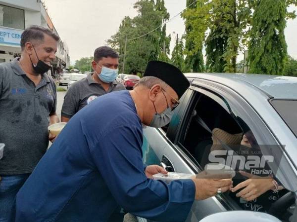 Penduduk setempat yang melalui kawasan tapak Pasar Malam Kampung Muhibbah Sungai Siput pada Sabtu menerima agihan bubur lambuk dan kurma disampaikan Mohd Zolkafly.