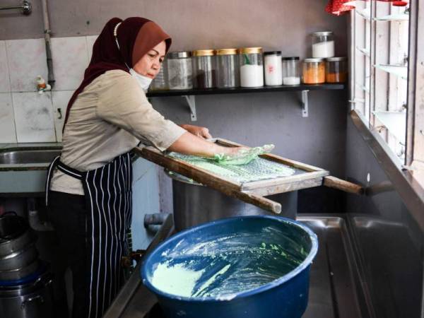 Peniaga Bubur Anak Lebah, Sarpah Salwa Abd Rahim, 57, menekan adunan tepung di atas peralatan acuan untuk menghasilkan bentuk seperti anak lebah ketika proses memasak bubur Anak Lebah di rumahnya di Taman Perpaduan. - Foto Bernama