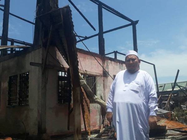 Ahmad Shazali di hadapan deretan tiga buah rumah di Pusat Pengajian Islam Fauzi yang hangus di Kampung Sungai Udang, Yan pada Jumaat.