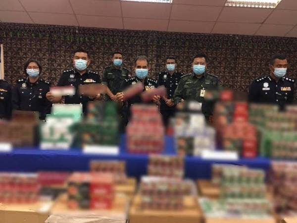 Abdul Majid (tengah) melihat rokok dan minuman keras pelbagai jenama yang dirampas ketika sidang akhbar di Ibu Pejabat Polis Kontinjen (IPK) Melaka pada Isnin.