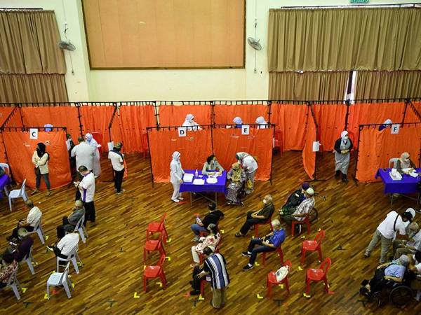 Warga emas dan golongan berisiko menerima suntikan vaksin Pfizer-BioNTech pada hari pertama fasa kedua Program Imunisasi COVID-19 Kebangsaan di Wisma Belia, hari ini.