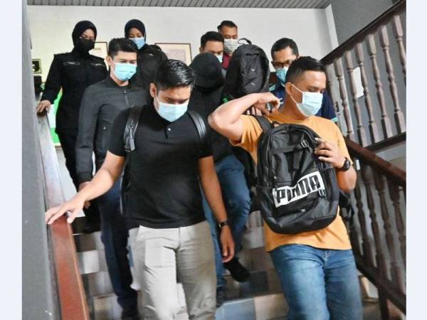 Tertuduh (tengah) ketika dibawa ke pekarangan Mahkamah sesyen Melaka pada Selasa.