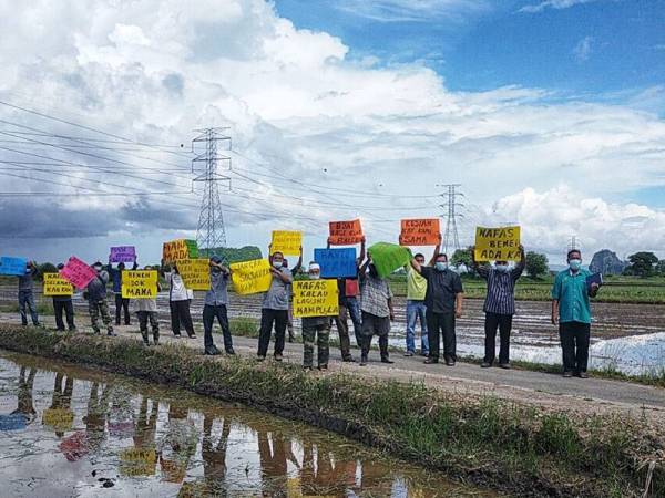 Pesawah di Kampung Pulau Kabu, Siputeh memegang sepanduk sebagai tanda protes terhadap kelewatan benih padi di kawasan mereka.