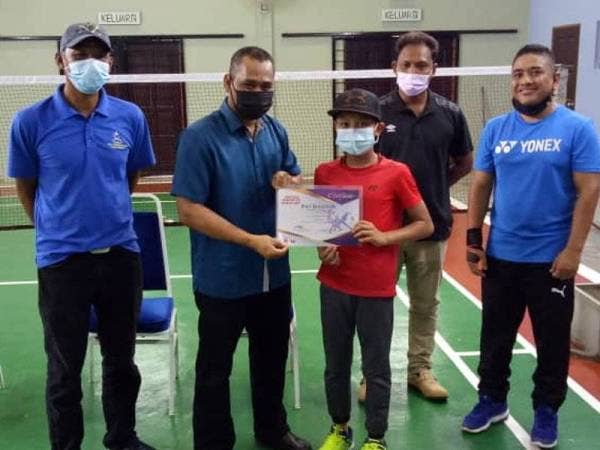 Suhairi menyampaikan sijil kepada peserta Bentong Badminton Champ 2021, Muhammad Aliff Jamil, 11, disaksikan Khairuddin (kiri) di Dewan Serbaguna Kampung Kuala Repas, Chamang Bentong.