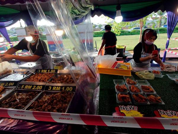 Setiap gerai dipisahkan dengan plastik lutsinar dan pita keselamatan untuk mengekalkan penjarakan fizikal antara peniaga dan pelanggan semasa tinjauan foto Bernama di Bazar Ramadan KotaSAS hari ini. 