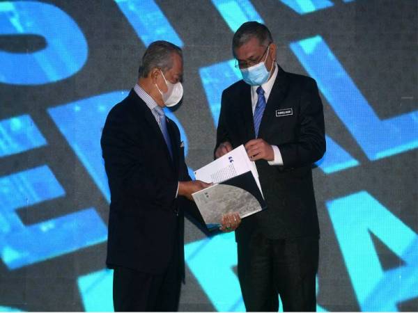 Shamsul Anuar (kanan) dan Muhyiddin (kiri) melihat isi kandungan buku Kerangka Pelan Transformasi Industri Mineral Negara 2021-2030 selepas melancarkan pelan tranformasi tersebut, pada Khamis. - Foto Bernama