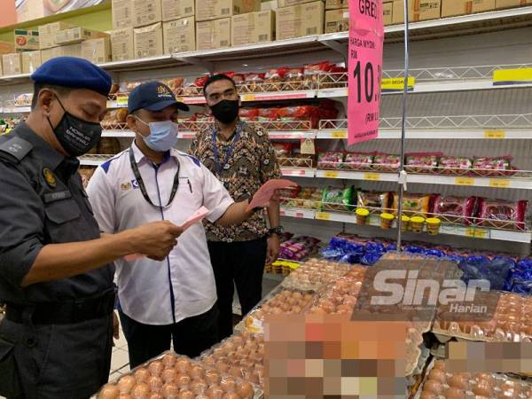 Adnan (dua, kiri) melihat telur yang dijual di sini pada Khamis.