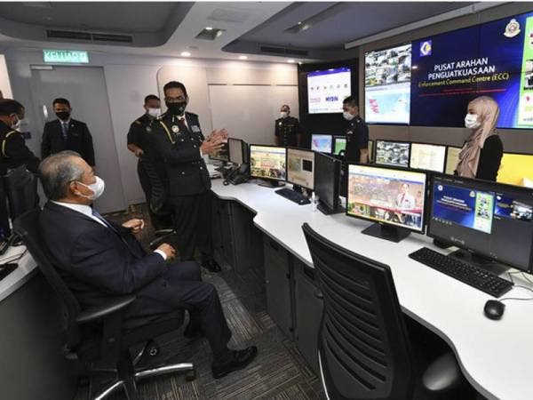 Muhyiddin (kiri) mendengar penerangan daripada Pengarah Penguatkuasa KPDNHEP, Azman Adam mengenai ECC ketika lawatan ke KPDNHEP hari ini.