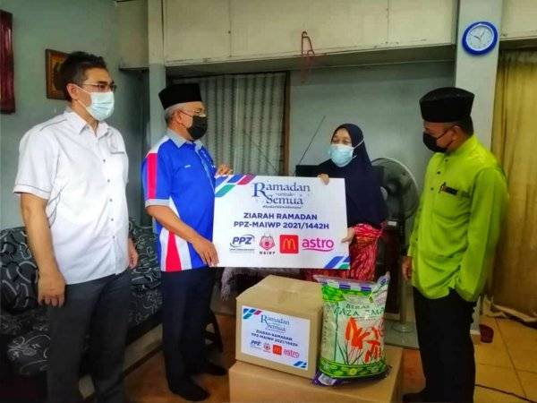 Azhar (kiri), Abdul Hakim (dua dari kiri) dan Mohd Nizam menyampaikan sumbangan kepada asnaf, Jauriah Bidin dalam program Ziarah Ramadan yang diadakan pada Jumaat.