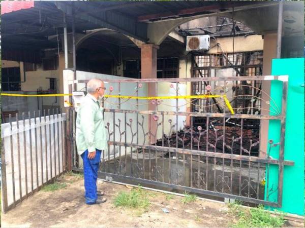 Mohd Fauzi melihat sisa kebakaran dari luar pagar rumahnya di Taman Fajar, Panji, Kota Bharu.