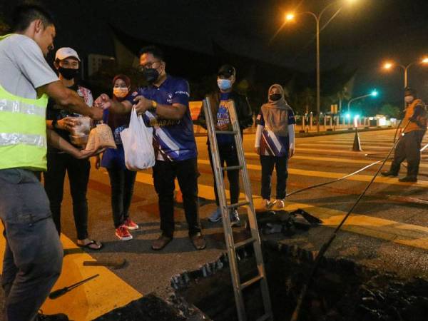 Mohd Nizam(berbaju biru) memberi juadah sahur kepada Mohamad Shahril.