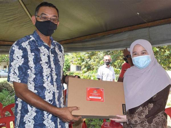 Nurul Fatin Nabihah (kanan) menerima sumbangan komputer riba daripada Rosol di kediamannya di Kampung Tengkawang pada Isnin. - Foto Bernama