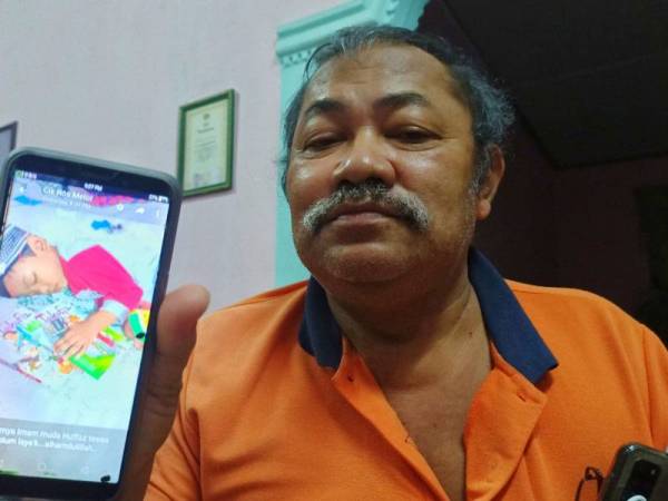 Che Mohd Noor Awang menunjukkan gambar terakhir cucunya, Muhammad Huffaz Wafri yang diambil pada Ahad malam.