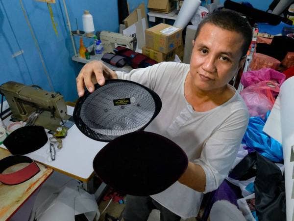 Pemilik Pustaka Al Jilani, Hamzah Irzal, 52 menunjukan songkok yang selesai dijahit oleh beliau. - Foto Bernama