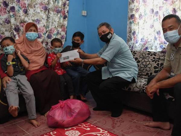 Khairul Azlam (dua dari kanan) menyampaikan sumbangan kepada Zainab (dua dari kiri) pada program Ziarah Kasih Ramadan di Kampung Gong Merawang, Marang pada Isnin. - FOTO: BERNAMA