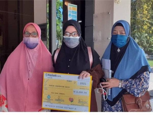 Balu mangsa, Nur Hazwani Nadirah Mat Hanipah,28 (tengah) menerima cek bayaran faedah pengurusan mayat di sebuah kilang memproses balak di Jabi,Pokok Sena, pada Ahad lepas.