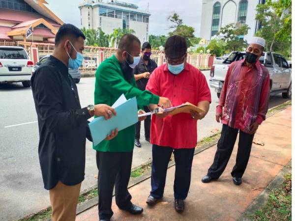 Mohammad Azlan (dua dari kiri) berbincang sesuatu dengan Penasihat Undang-undangnya, Mohd Ali Akbar Yusoff (baju merah) dan salah seorang kakitangannya, Mohd Mustakim Abdullah@Ali (baju hitam) di hadapan Kompleks Mahkamah Tinggi, Sesyen dan Majistret Kuala Terengganu, pada Rabu.