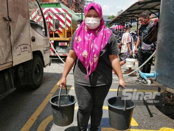 Norashikin mengangkut air untuk kegunaan harian sementara bekalan air disambung semula.