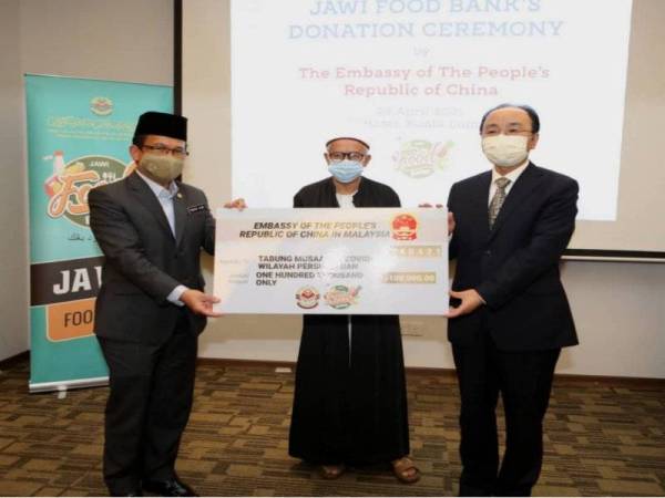 Penyerahan replika cek disampaikan oleh Yujing (kiri) kepada Mohd Ajib sambil disaksikan Zulkifli.