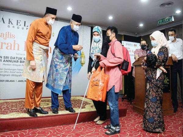 Annuar (dua, kiri) bersama Mohamed Faroz (kiri) menyerahkan sumbangan kepada OKU pada Majlis Fitrah Kasih anjuran Jakel di Jakel Mall.