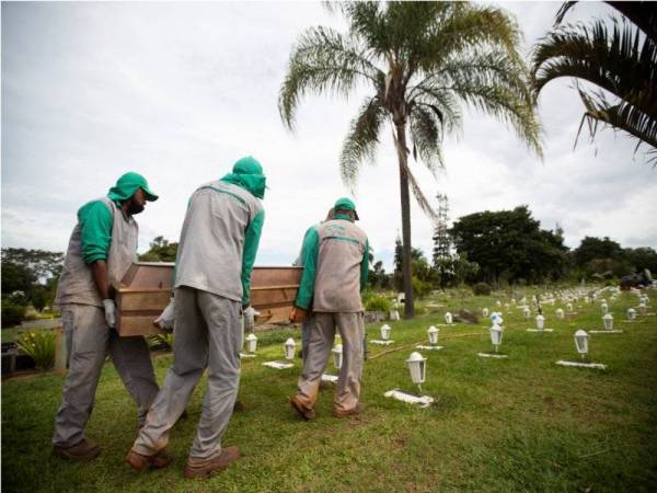 Pekerja pengurusan mayat mengangkat keranda mangsa Covid-19 di Brazil untuk dikebumikan. Foto: EPA