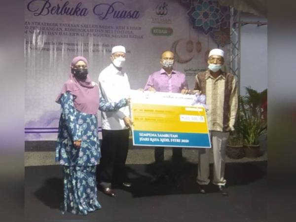 Wan Romani (dua dari kiri) menyerahkan 'mock cheque' baucar daging raya kepada Pengarah Yayasan Salleh Saidin, Abdul Azid Husin sambil disaksikan Mohd Salleh pada Majlis Berbuka Puasa di Kompleks Penerangan dan Penyiaran Sultan Abdul Halim, pada Khamis.