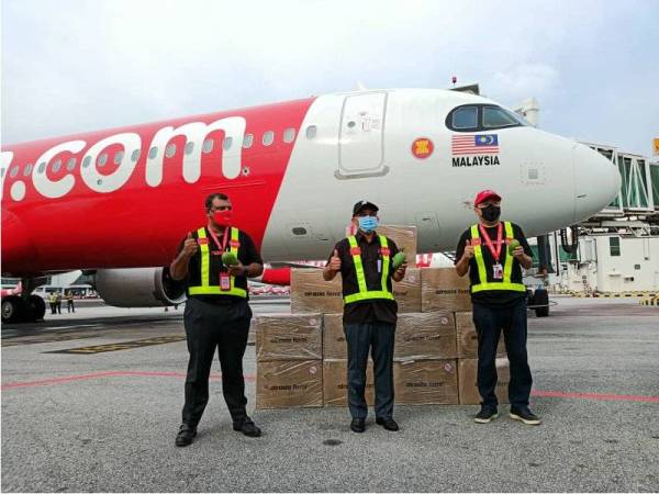 Tony (dari kiri), Ronald dan Kamarudin menunjukkan harumanis sebagai gimik majlis pelepasan penghantaran buah mangga ekslusif itu le Sabah di KLIA 2 pada Khamis.