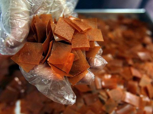 Pengeluar makanan ringan Nini Dzuraini Abdullah menunjukkan kepingan kecil makanan ringan kerepek lobak merah 'Cravia'. - Foto Bernama