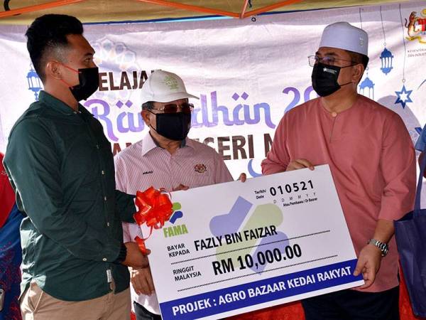Ketua Menteri Melaka, Datuk Seri Sulaiman Md Ali (kanan) dan Timbalan Menteri Pertanian dan Industri Makanan I Datuk Seri Ahmad Hamzah (tengah) menyerahkan replika cek berjumlah RM10,000 kepada peserta Agro Bazar Kedai Rakyat, Fazli Faizar (kiri) pada Program Jualan MyRakyat 'Melaka Agro Market' di Pasar Tani Masjid Tanah di sini, hari ini.