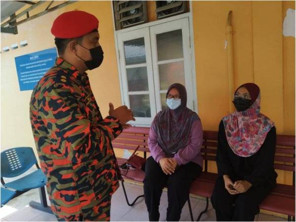 Iqbal (kiri) bertanya sesuatu kepada Rohaya (duduk di kanan) ketika di pekarangan bilik forensik Hospital Pontian pada Sabtu.