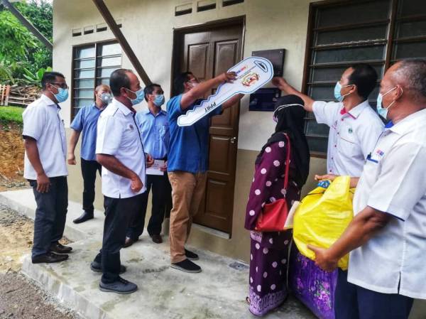 Abdul Rahman (empat, kanan) menyempurnakan simbolik perasmian penyerahan kunci rumah milik Noridahayati (tiga,kanan) di Kampung Tanjung Lipis, Isnin.