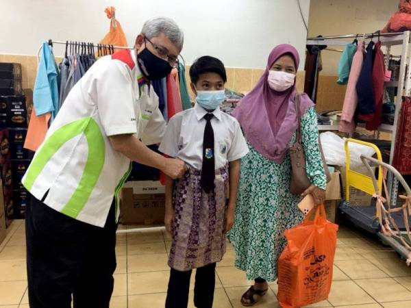 Ibrahim (kiri) memakaikan samping kepada salah seorang penerima ketika menghadiri program Pautan Kasih Ramadan bersama Anak-anak Fakir, Miskin dan Yatim anjuran Zakat Melaka di Bukit Baru, Melaka pada Selasa. - Foto Bernama